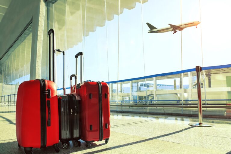 Resting Red & Black Luggage in Airport Terminal with View of Plane Flying, Airport Near Scenic Ridge | Pittsburgh New Home Connection